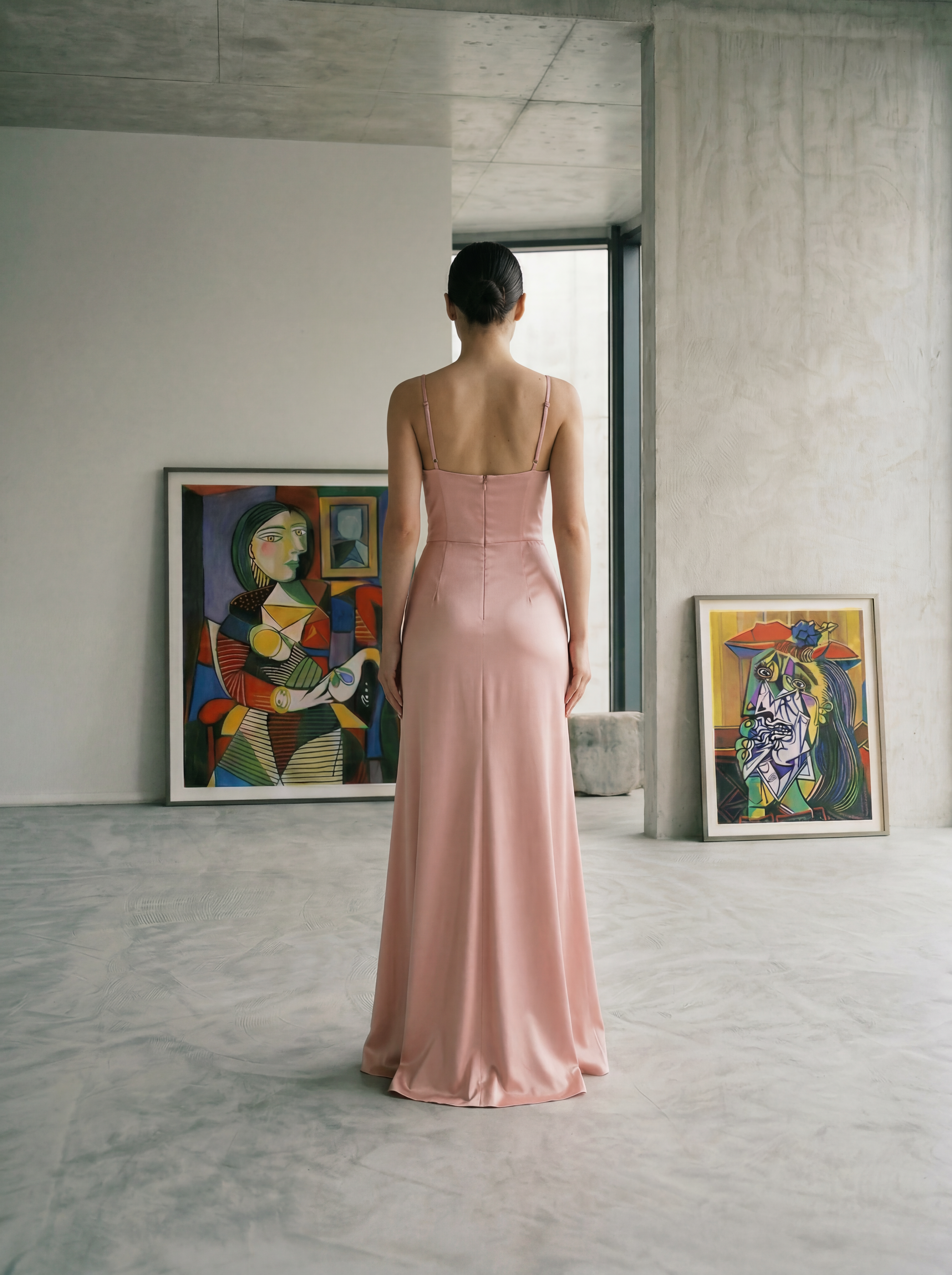 Woman in a blush bustier dress standing in a room with abstract art on the walls.