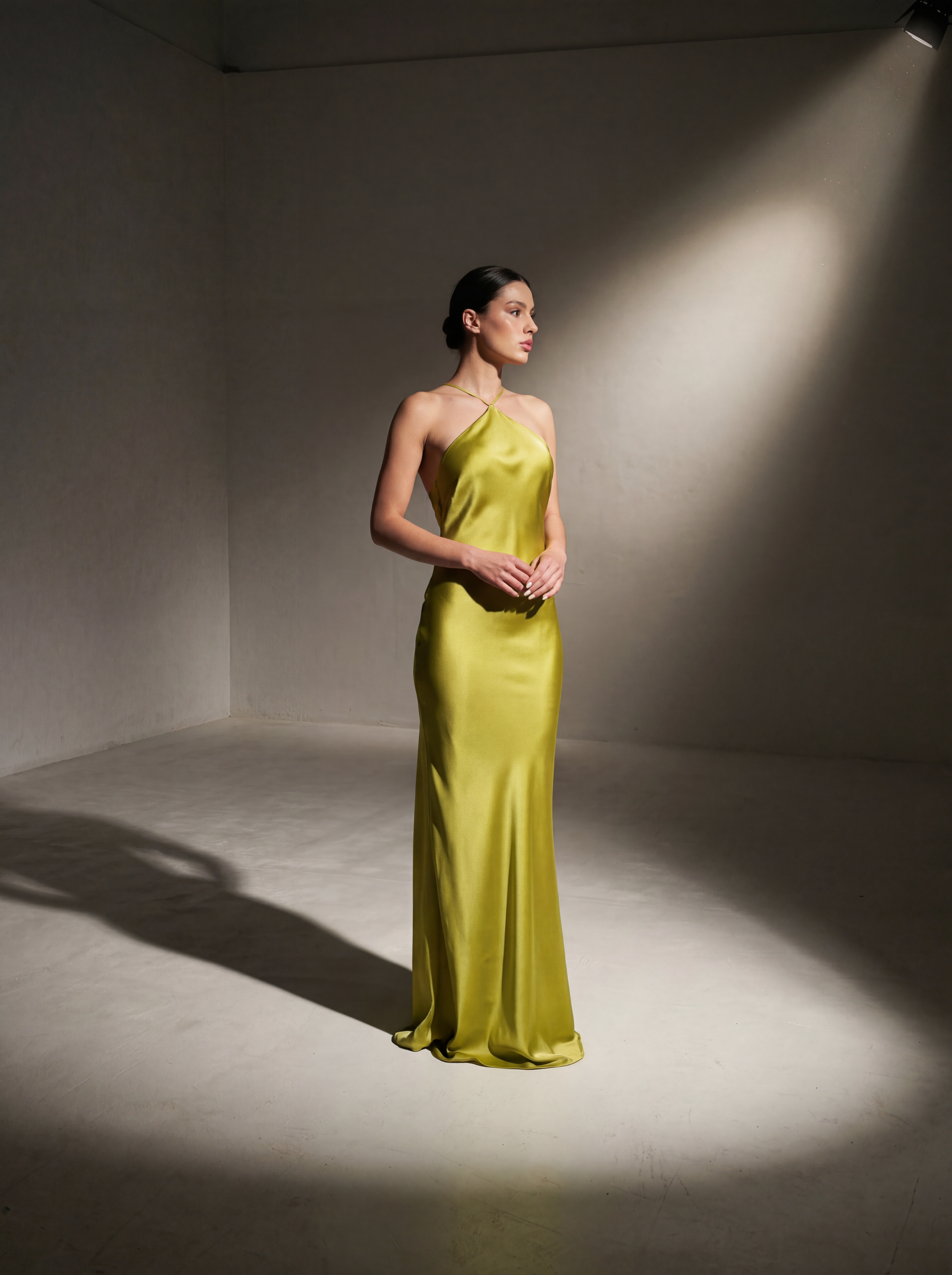Model wearing a floor-length chartreuse silk halter gown by Bella Monnar