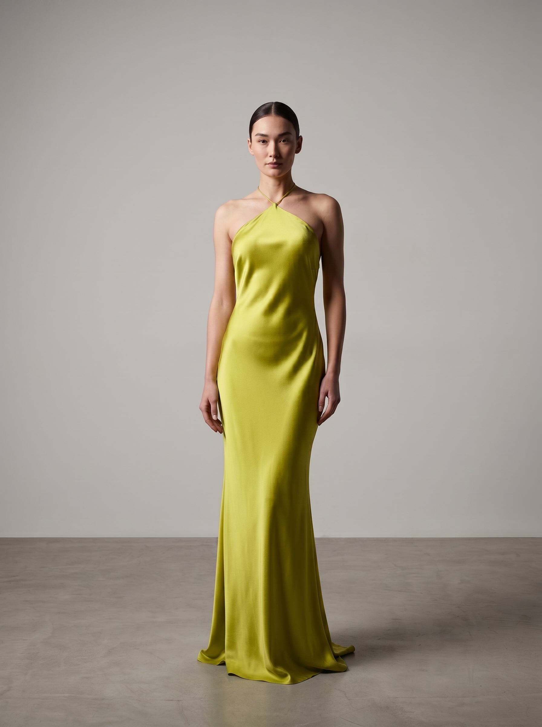 Woman wearing a bright lime evening gown against a plain background